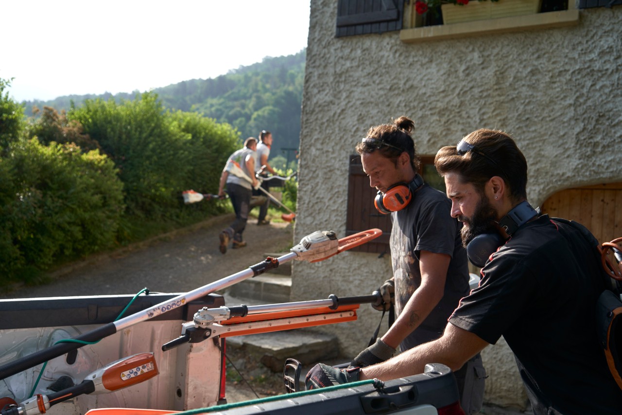 Жулиен Локуарели, ландшафтен дизайнер, разтоварва оборудването на STIHL от превозното средство заедно с колегите си.