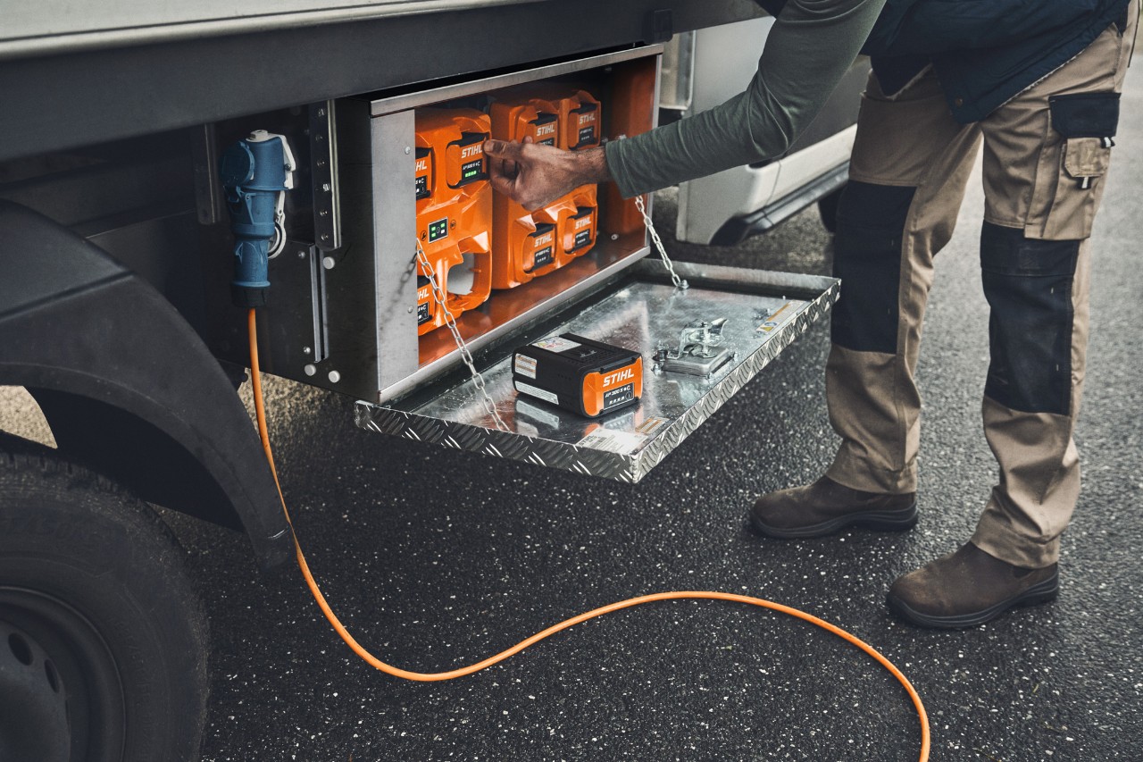 Мъж изважда заредена акумулаторна батерия STIHL AP 500 от кутията за зареждане 