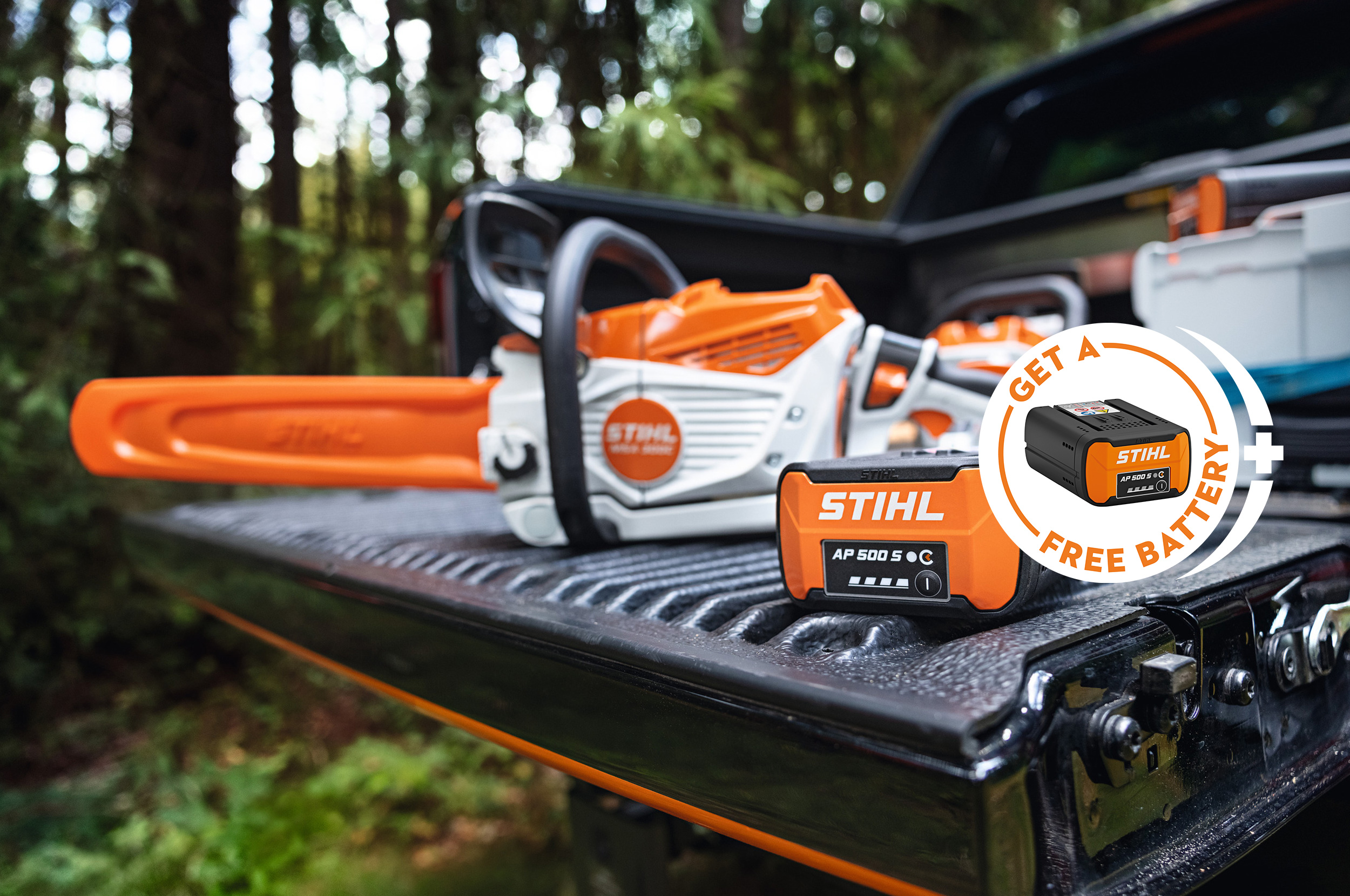 STIHL AP 500 S battery on the loading area of a pickup together with the new STIHL MSA 300 battery chainsaw, additional badge with STIHL battery and the inscription "Get a free battery"