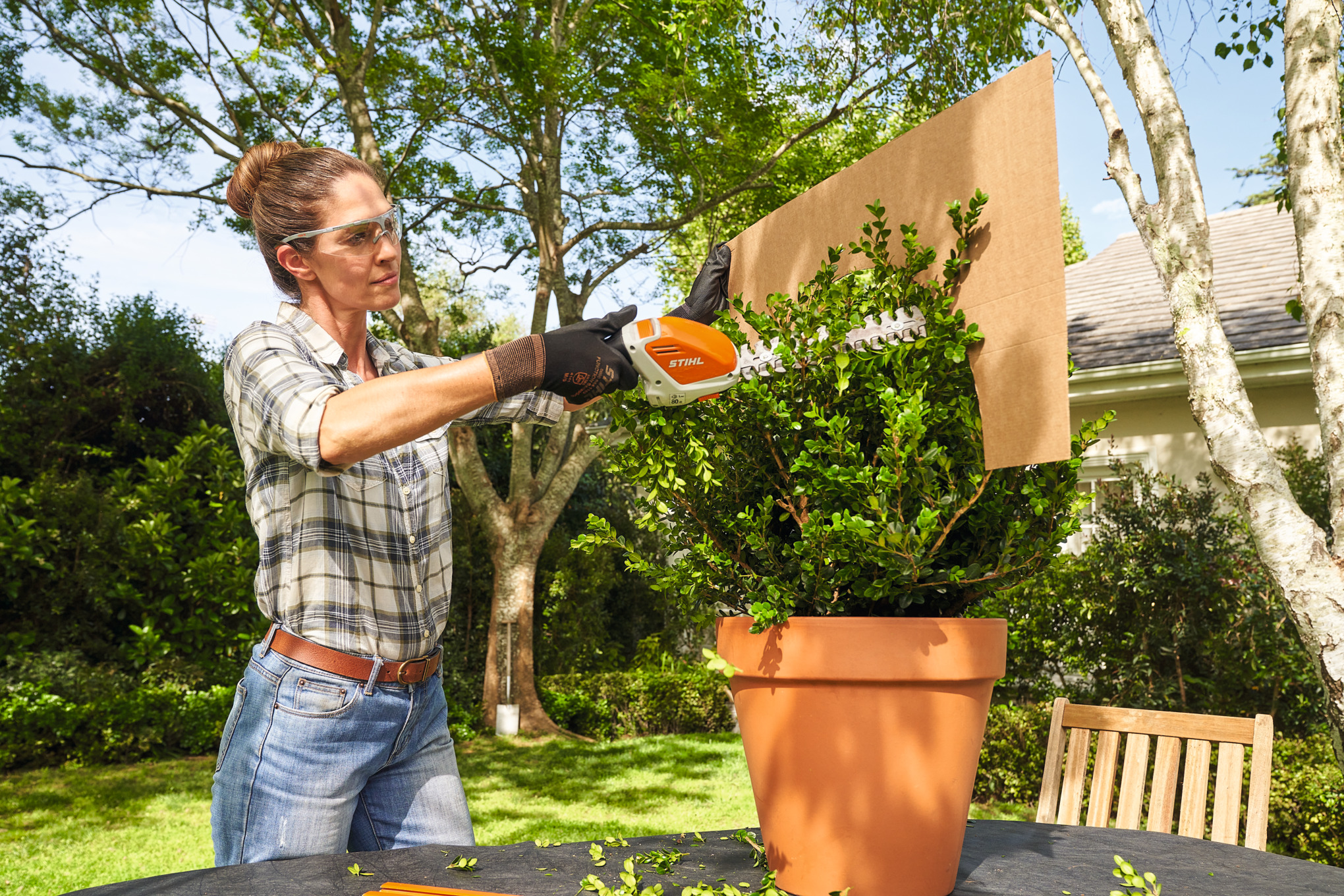 Жена подрязва чемшира с акумулаторната ножица за храсти STIHL HSA 26 с помощта на картонен шаблон в сферична форма