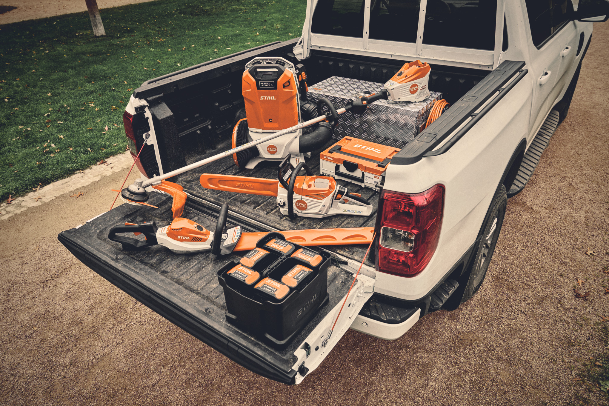 Различни акумулаторни уреди от системата STIHL AP и подходящите акумулаторни батерии на товарната платформа на автомобил
