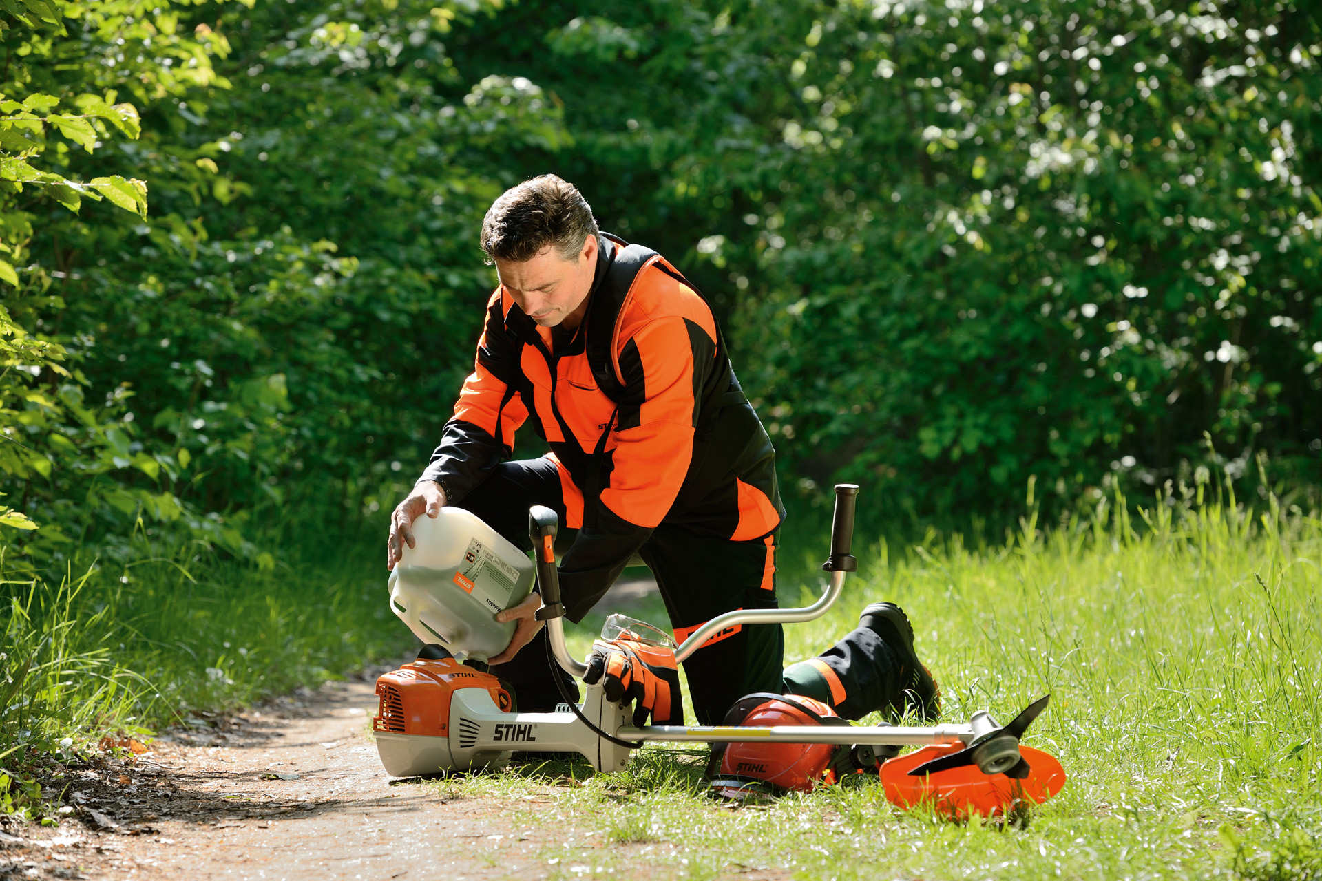 Мъж зарежда моторна коса STIHL със смес от бензин и масло