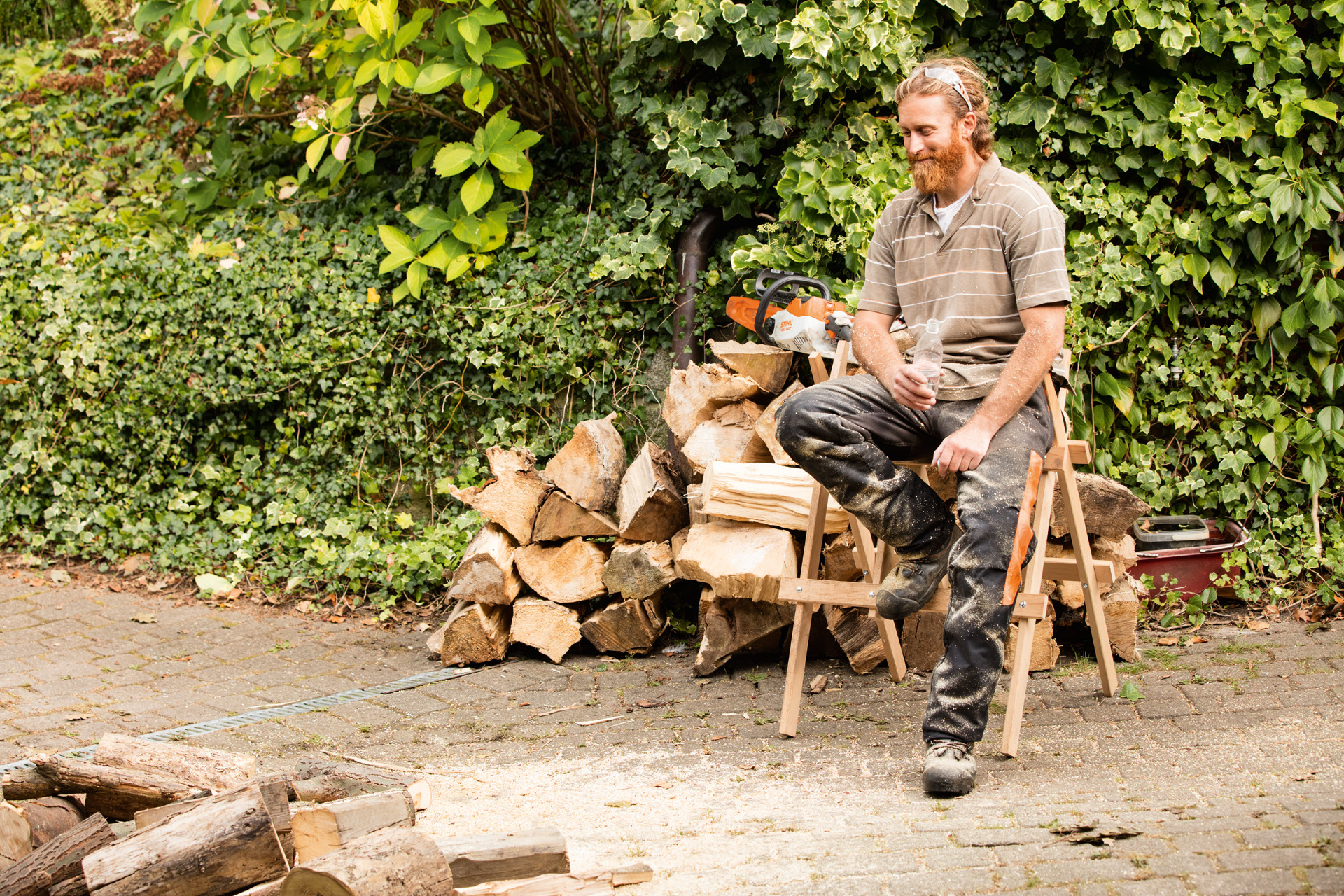 Мъж седи на станок пред дървен ствол