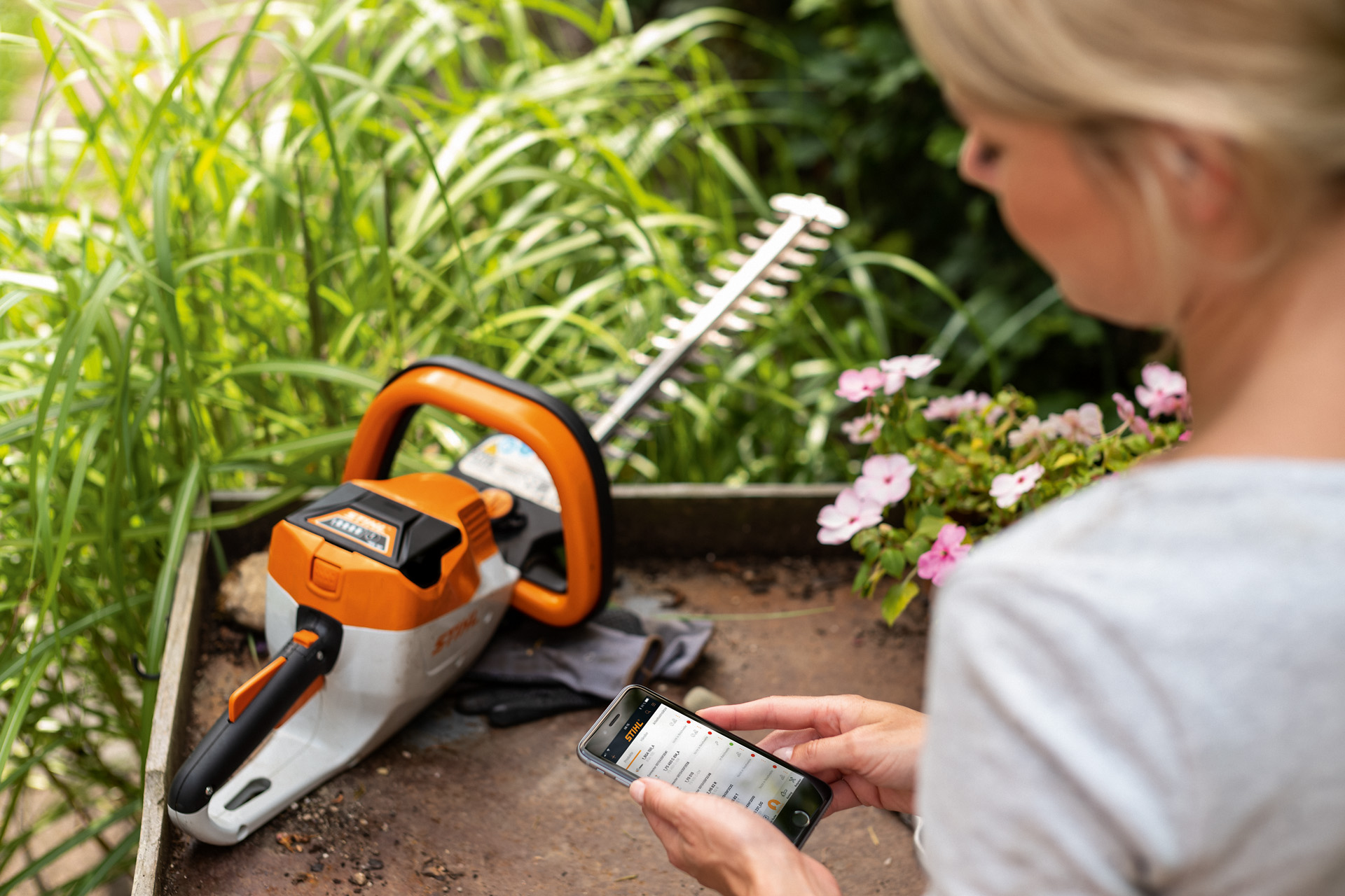 Жена регистрира своята ножица за жив плет STIHL с приложението STIHL на смартфон