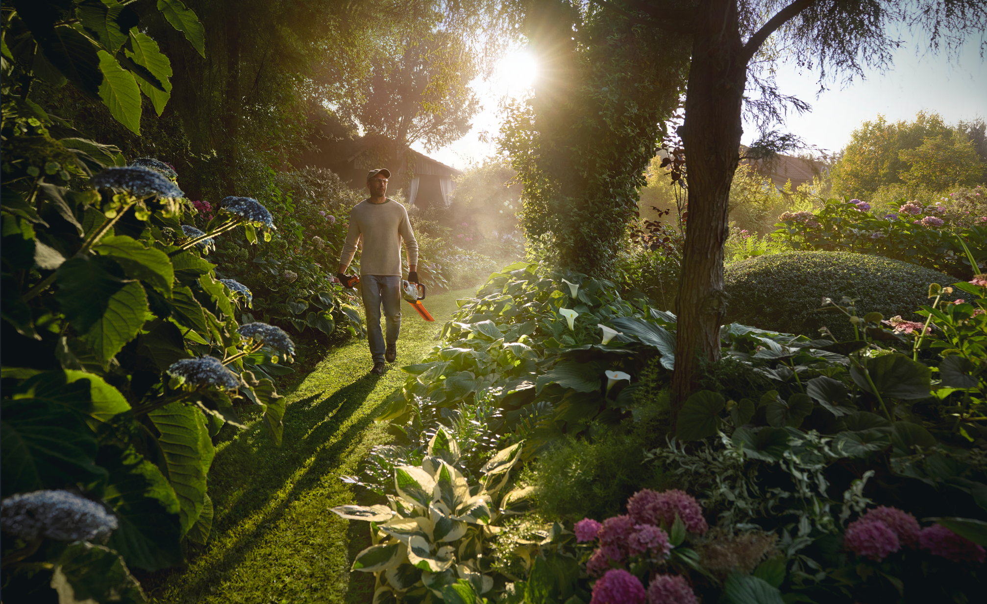 Мъж с ножица за жив плет в ръка се разхожда в градина