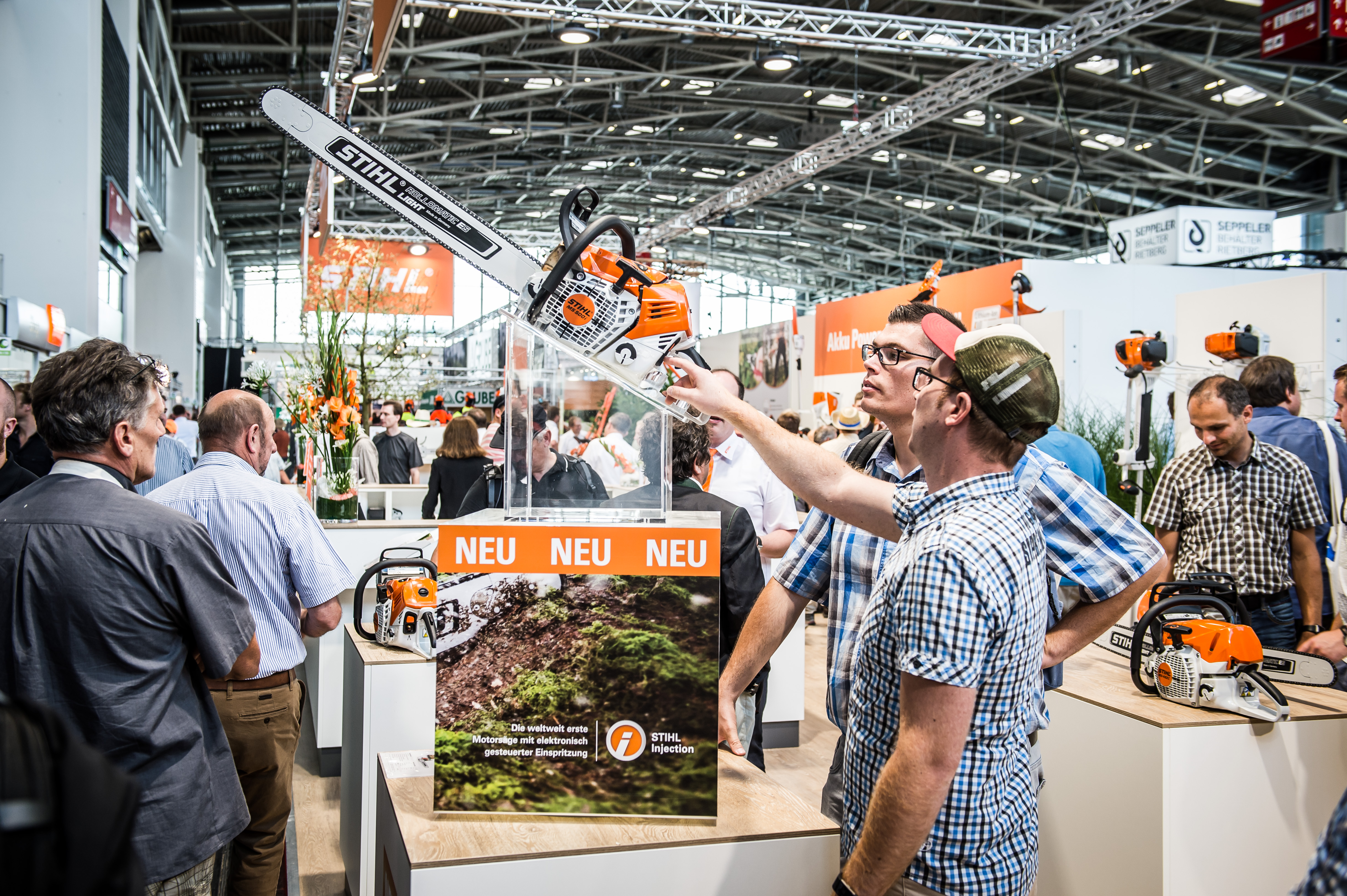 Посетители на щанда на STIHL на изложение разглеждат нови продукти, между които моторен трион STIHL